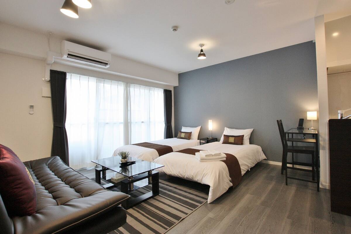 Una habitación de hotel con dos camas, un sofá, un escritorio y una silla.