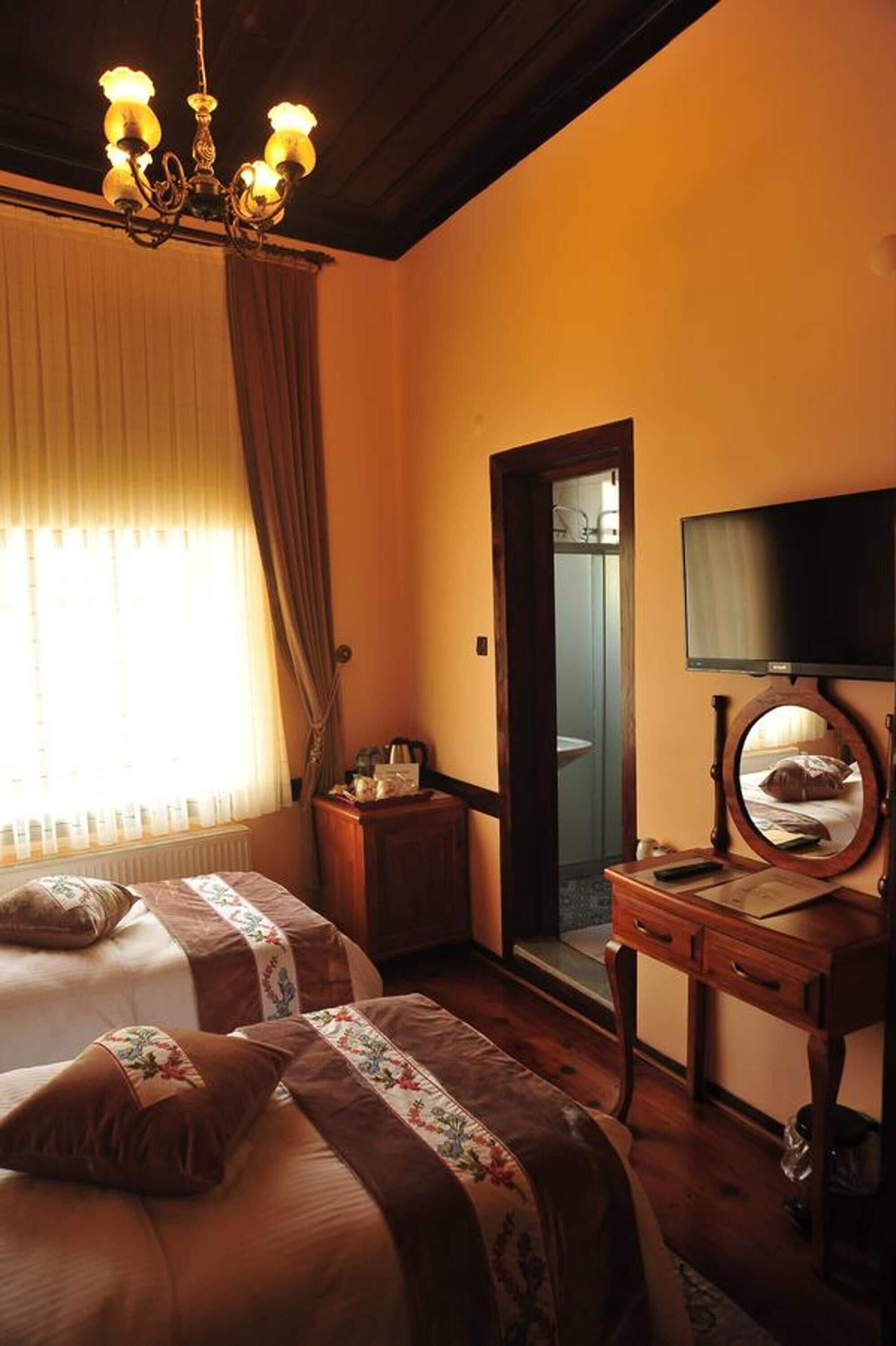 Une chambre d’hôtel avec deux lits, une commode en bois, une télévision et un miroir.