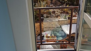 A balcony with a view of a landscaped garden, a stone wall, and a distant building. - B&B Il Giardino Di Armida (Ogliastro Cilento)