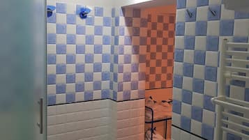 Bathroom features a checkered floor and tiled walls, with a towel rack and door.