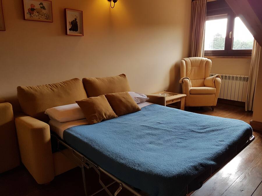 Una habitación de hotel con una cama, una silla, una mesita de noche y dos cuadros en la pared.