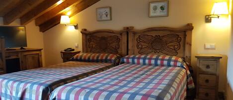 A double bed with a floral headboard, two bedside tables with lamps, and a television on a wooden cabinet.