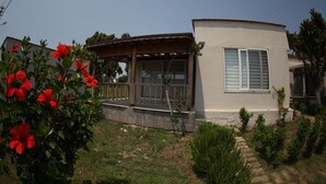 A single-story house with a covered porch, a small garden, and a clear sky. - Queenaba Beach (Erdemli)