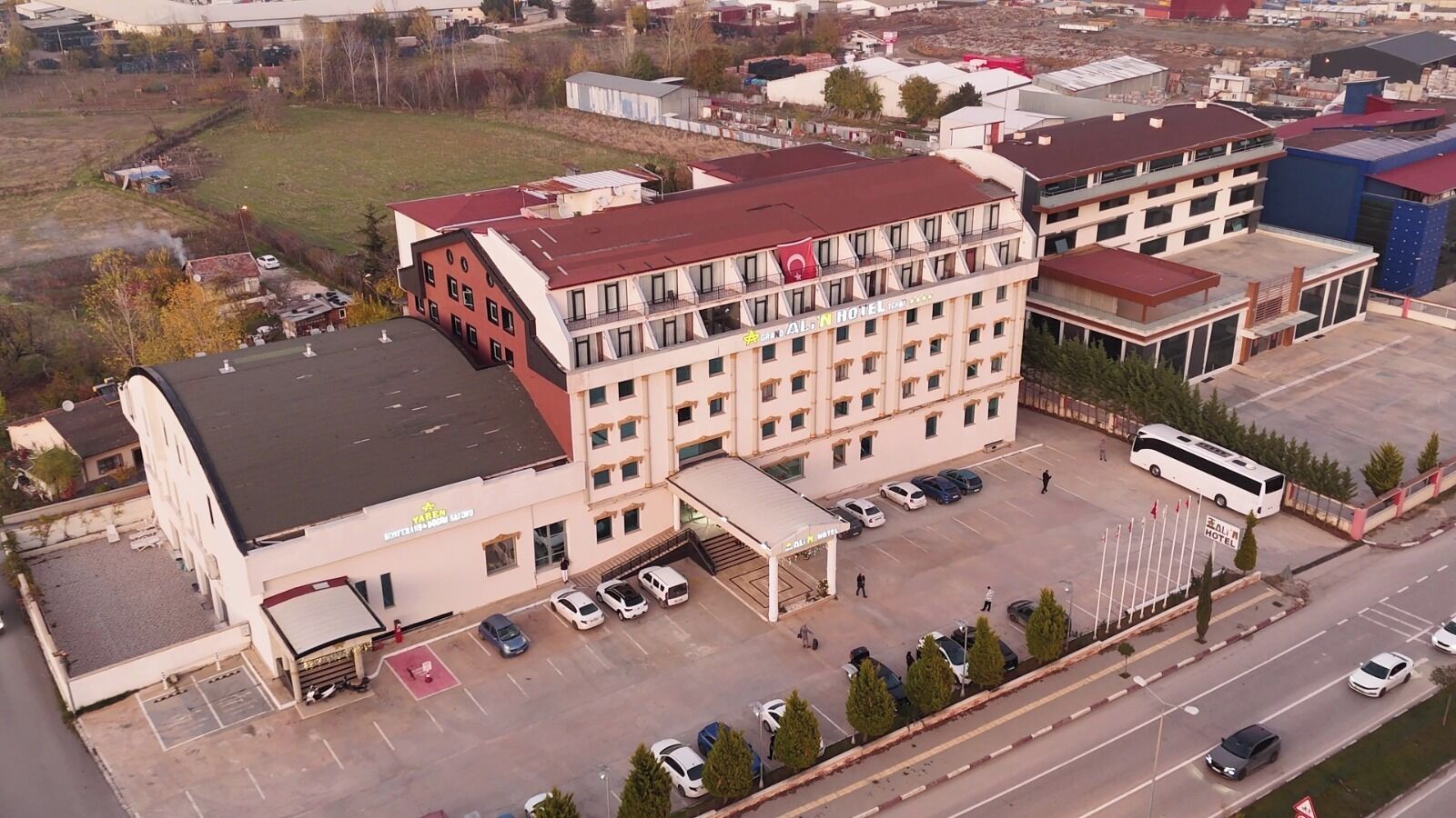 Een hotel met meerdere verdiepingen, een parkeerplaats en een busstation.