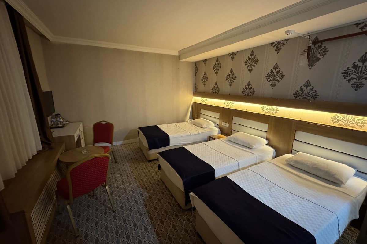 A hotel room with two beds, a desk, a chair, and a small table.