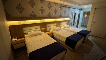 A hotel room with three beds, a wooden headboard, a patterned wallpaper, and a tiled floor.