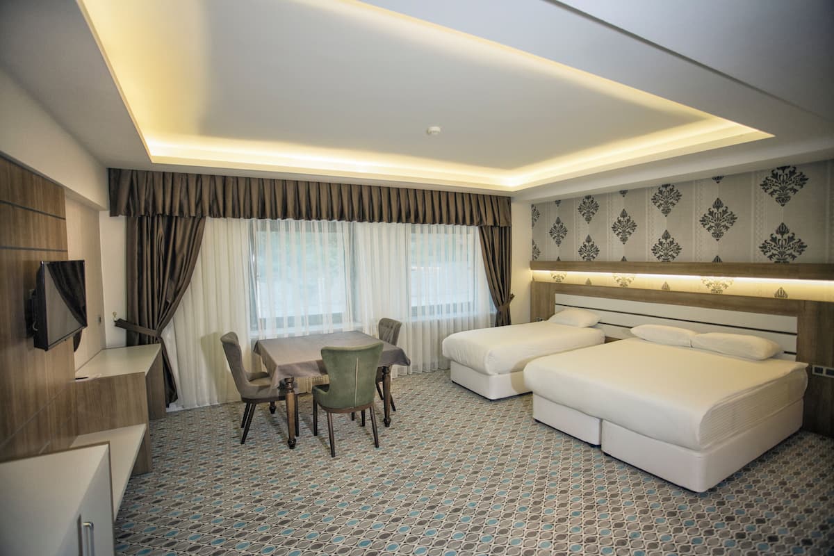 A hotel room with a dining table, two beds, and a TV.