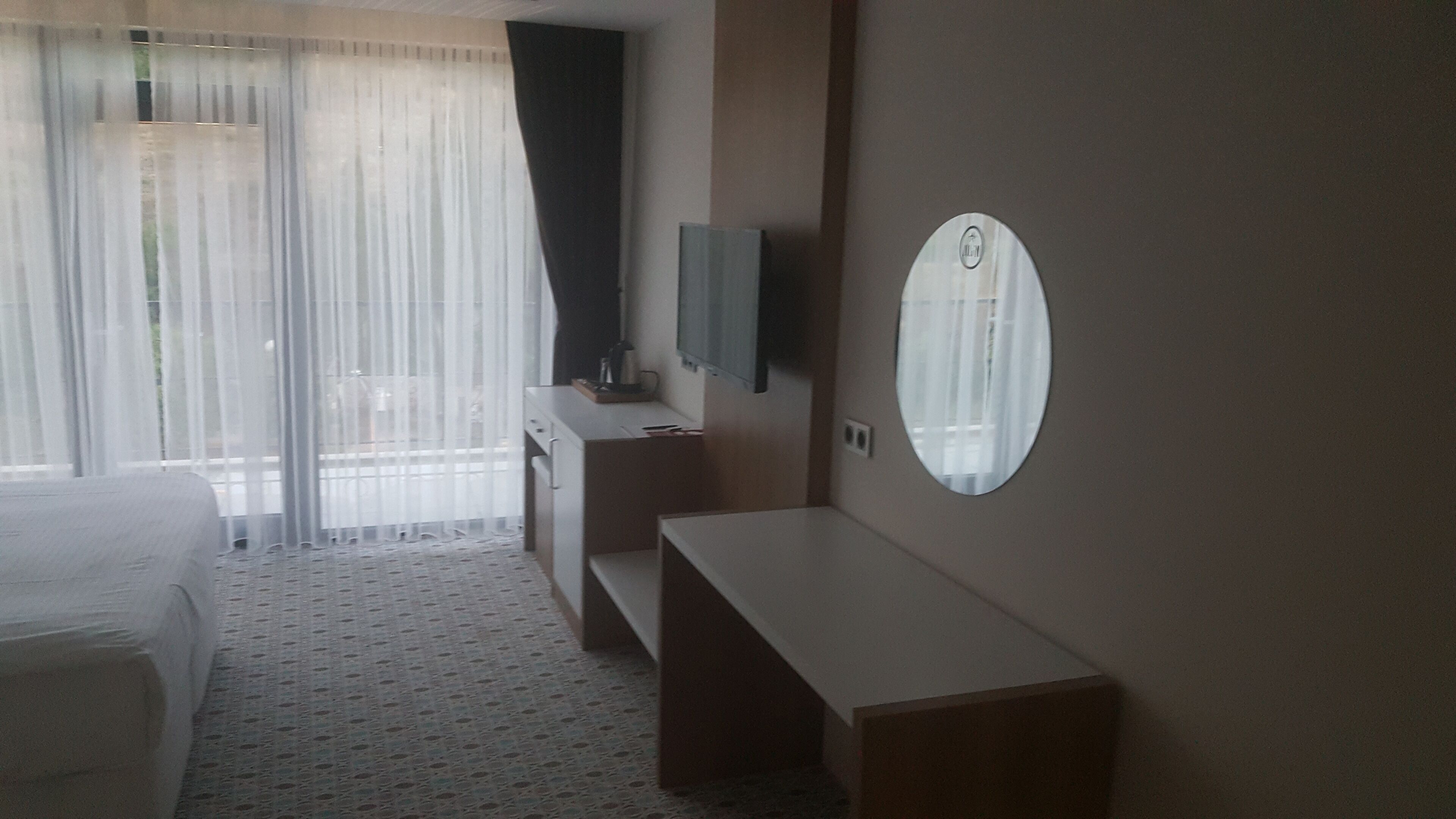 Ein Hotelzimmer mit Bett, Schreibtisch, Spiegel und Fernseher.