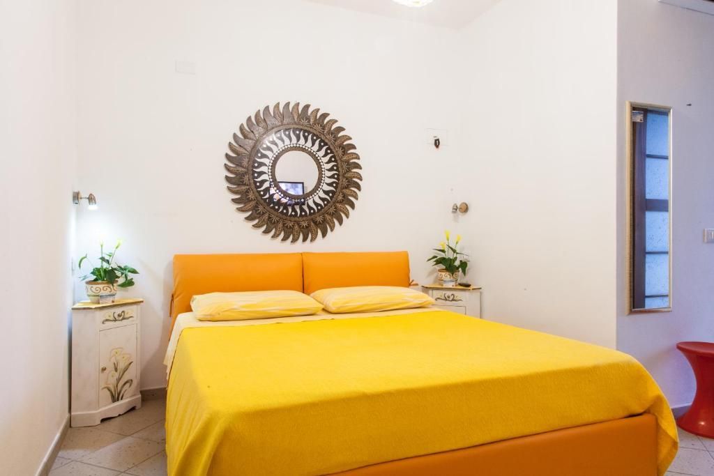 A bedroom with a bed, a mirror, a nightstand, and a window.