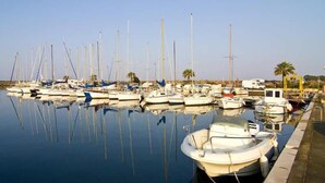 A marina with multiple boats docked, calm water, and a clear sky. - Affittacamere Al Mare (Oristano)