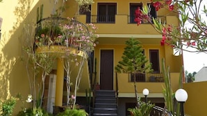 A yellow building with a balcony, a staircase, and various plants. - Affittacamere Al Mare (Oristano)