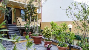 A courtyard with potted plants, a staircase, and a building facade. - Affittacamere Al Mare (Oristano)
