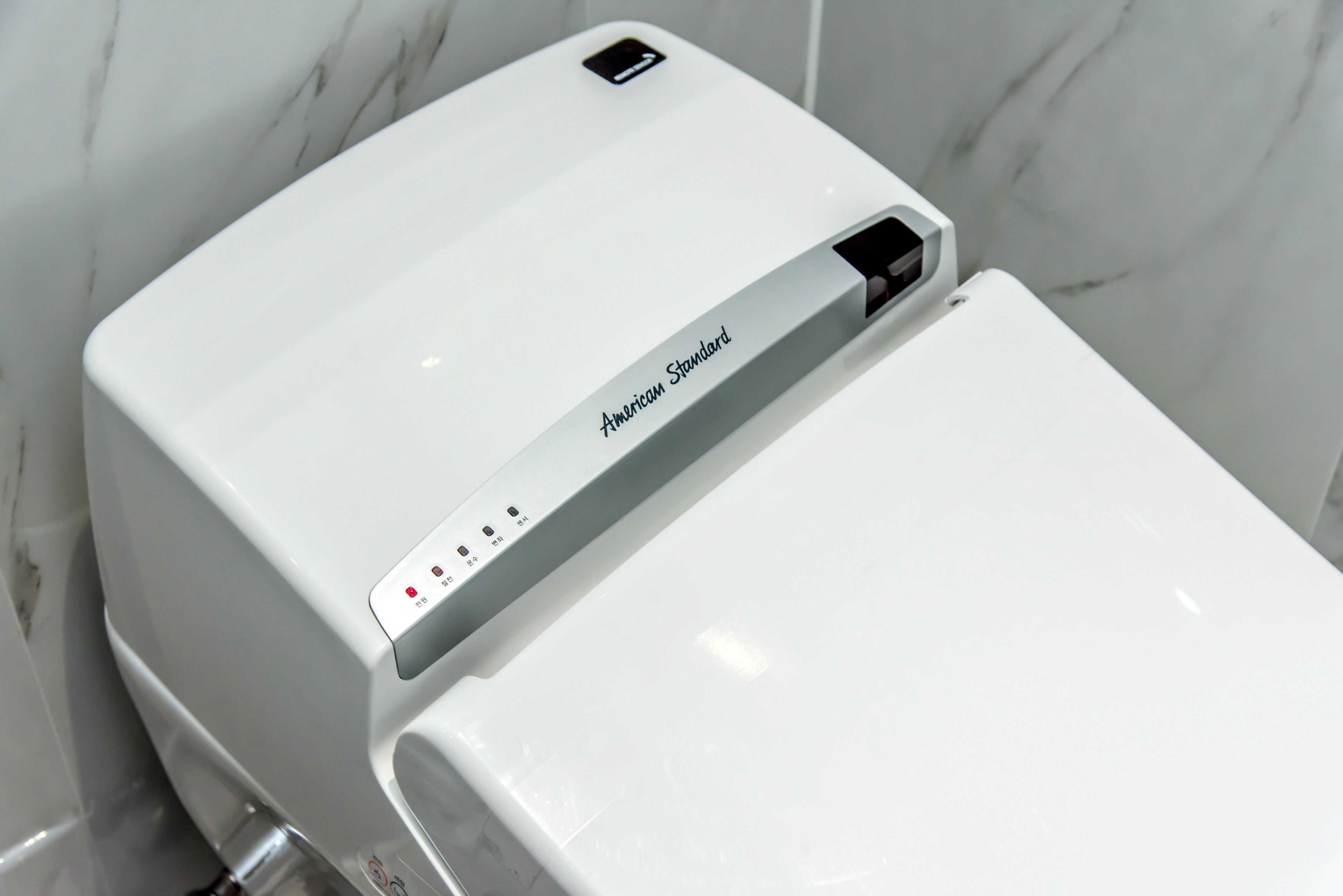 Een wit Amerikaans Standard toilet met een bedieningspaneel en een USB-poort.