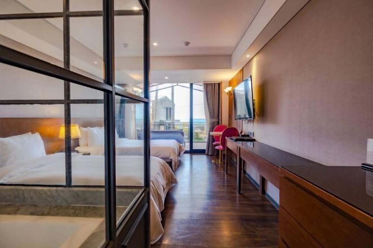 Une chambre d’hôtel avec un grand lit, un bureau, une chaise, une télévision et une vue sur l’extérieur.