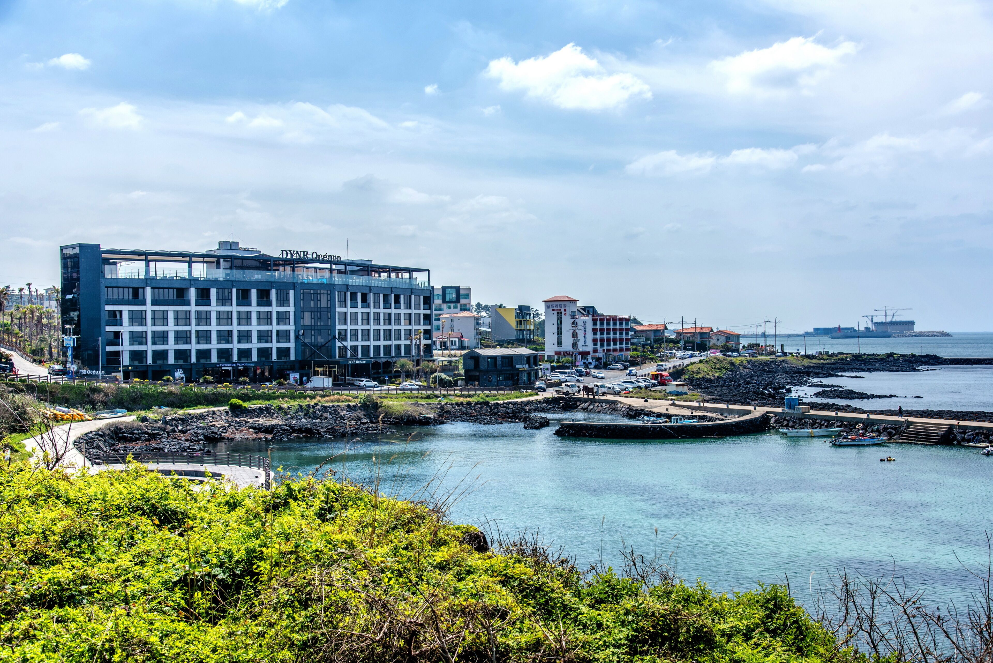 Um hotel costeiro com design moderno, localizado perto de um porto com barcos.