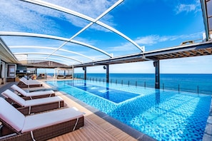 Cubierta de crucero con piscina, sillas de descanso y vista al océano.