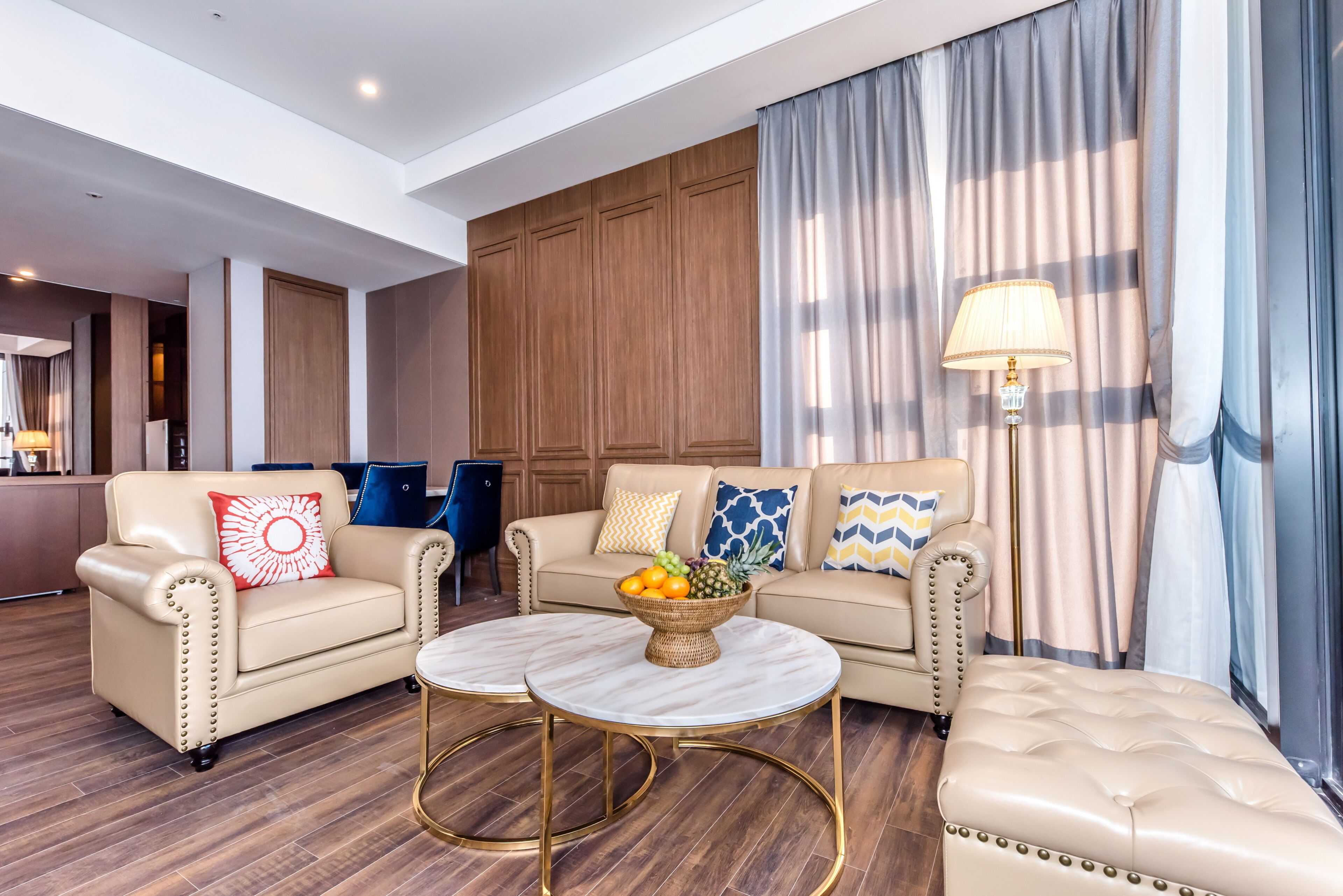 Une chambre d’hôtel moderne avec un canapé en cuir, une table basse ronde et un coin repas doté d’un buffet.