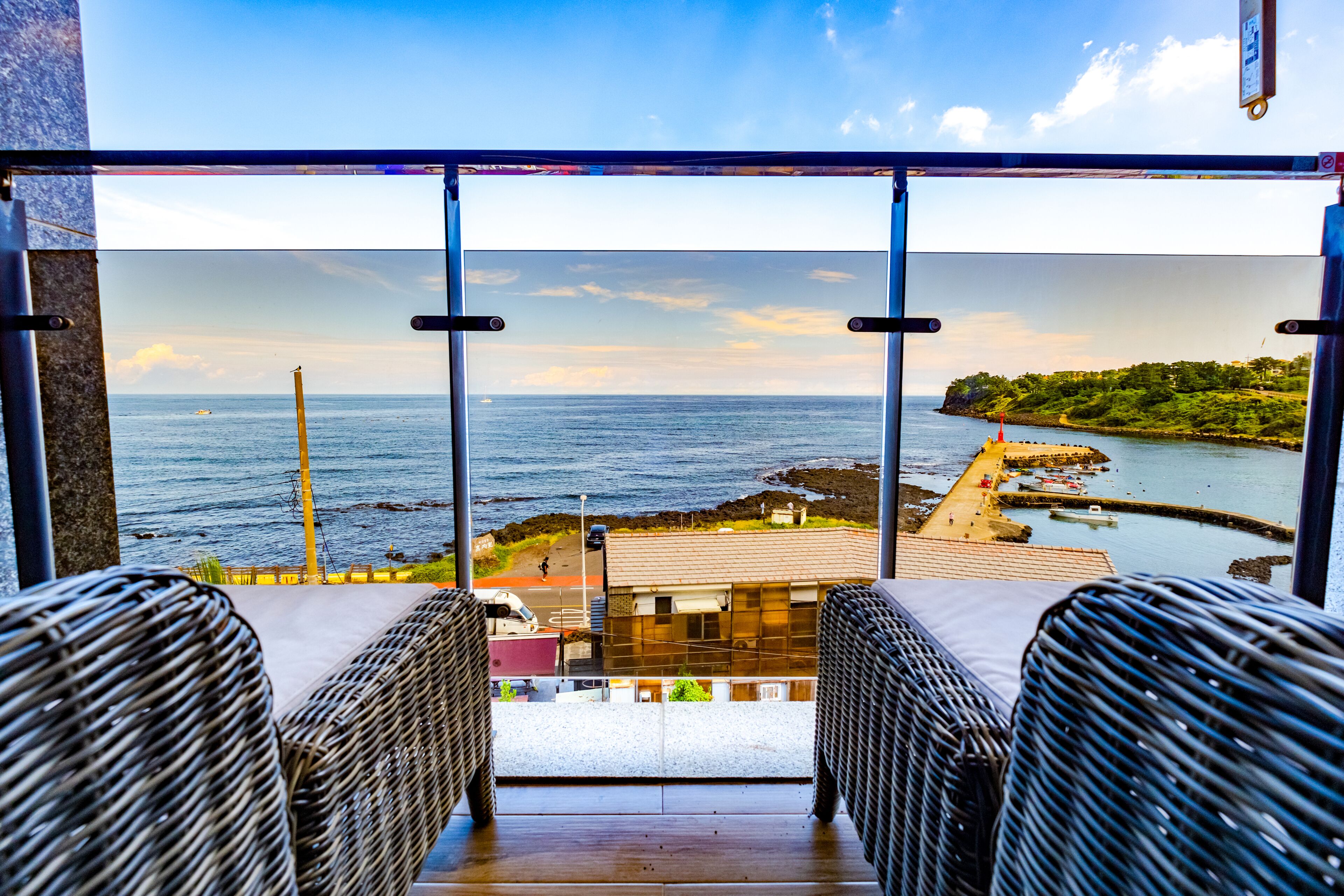 Un balcón con sillas de mimbre y vistas al mar y la costa.