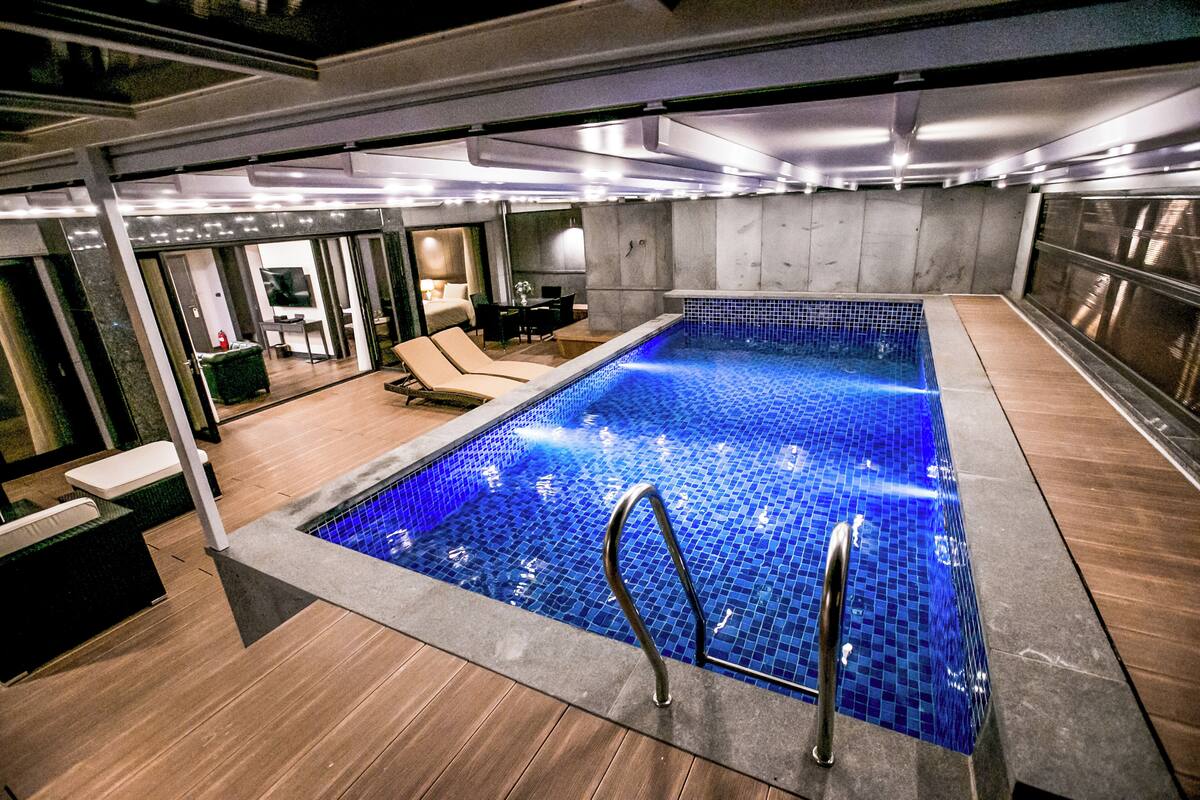 Une piscine intérieure moderne, dotée d’un sol carrelé, de chaises longues et d’un espace détente.