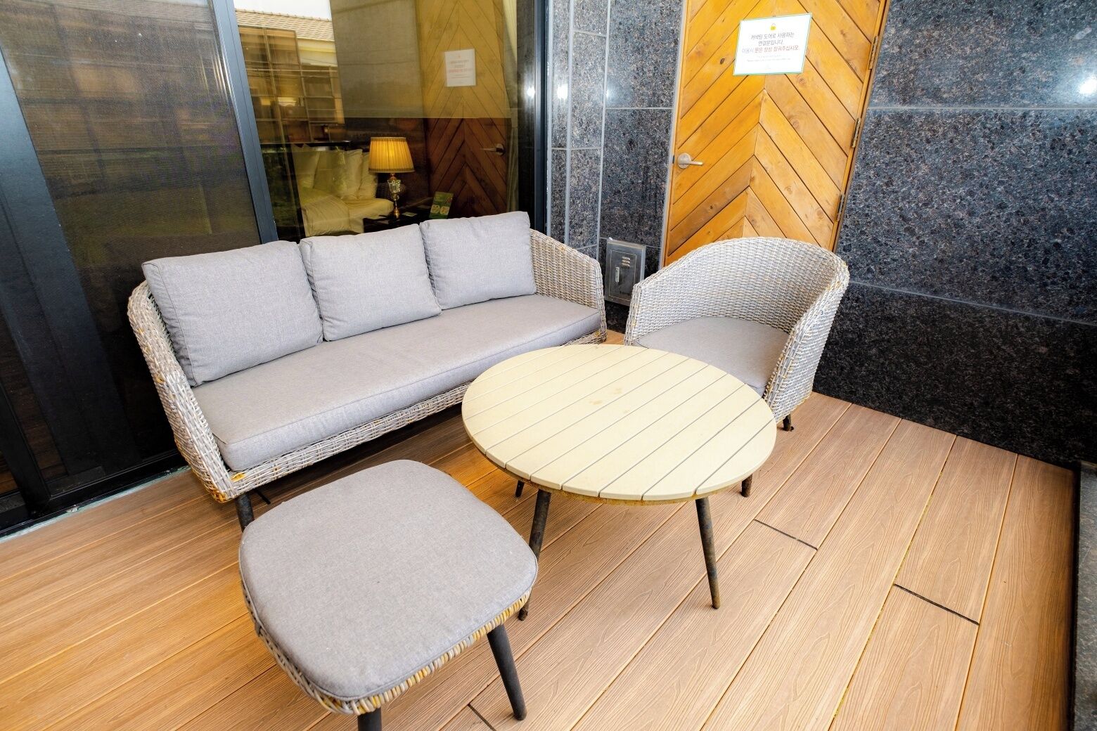 A corner seating area with a sofa and two chairs, a round table, and a wooden floor.