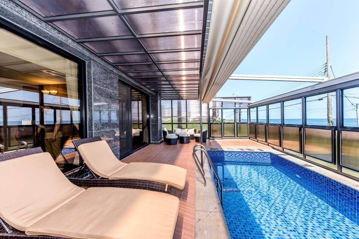 Une terrasse ensoleillée avec des chaises longues et une piscine.