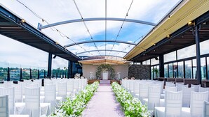 Un espace intérieur doté d’une allée centrale, de chaises blanches et d’une composition florale à l’extrémité.