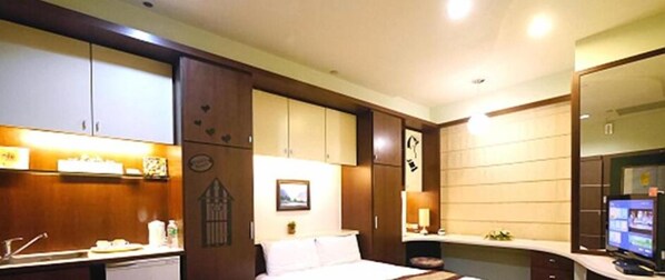 A hotel room with a bed, a desk, a television, and a large mirror. - 85 Happy Holiday (Kaohsiung)