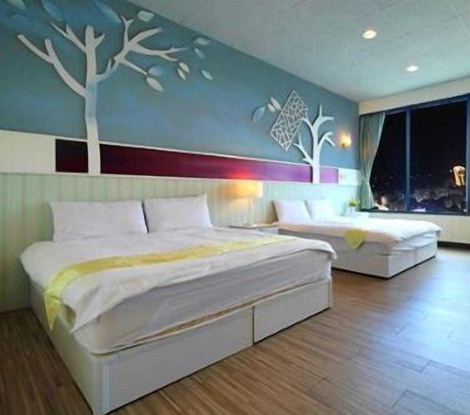 A hotel room with a large bed, a smaller bed, a nightstand, and a wall mural.