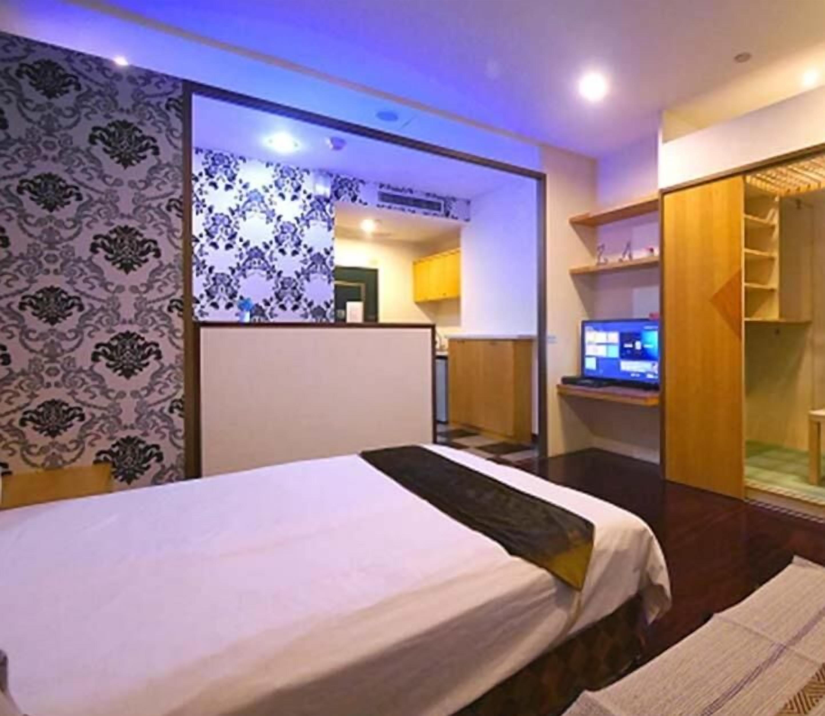Une chambre d’hôtel équipée d’un lit, d’une télévision, d’une armoire et d’une petite kitchenette.