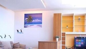 Una sala de estar moderna con un televisor de pantalla plana, estanterías de madera y un cuadro con una escena de playa.