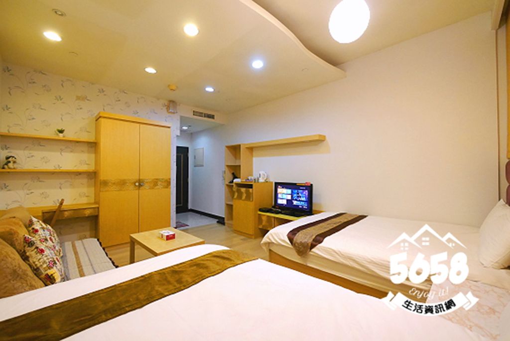 A hotel room with a bed, a desk, a television, and a wardrobe.