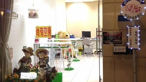 Entrada de hotel con letrero de neón, mostrador de recepción y adorno de oso de peluche.