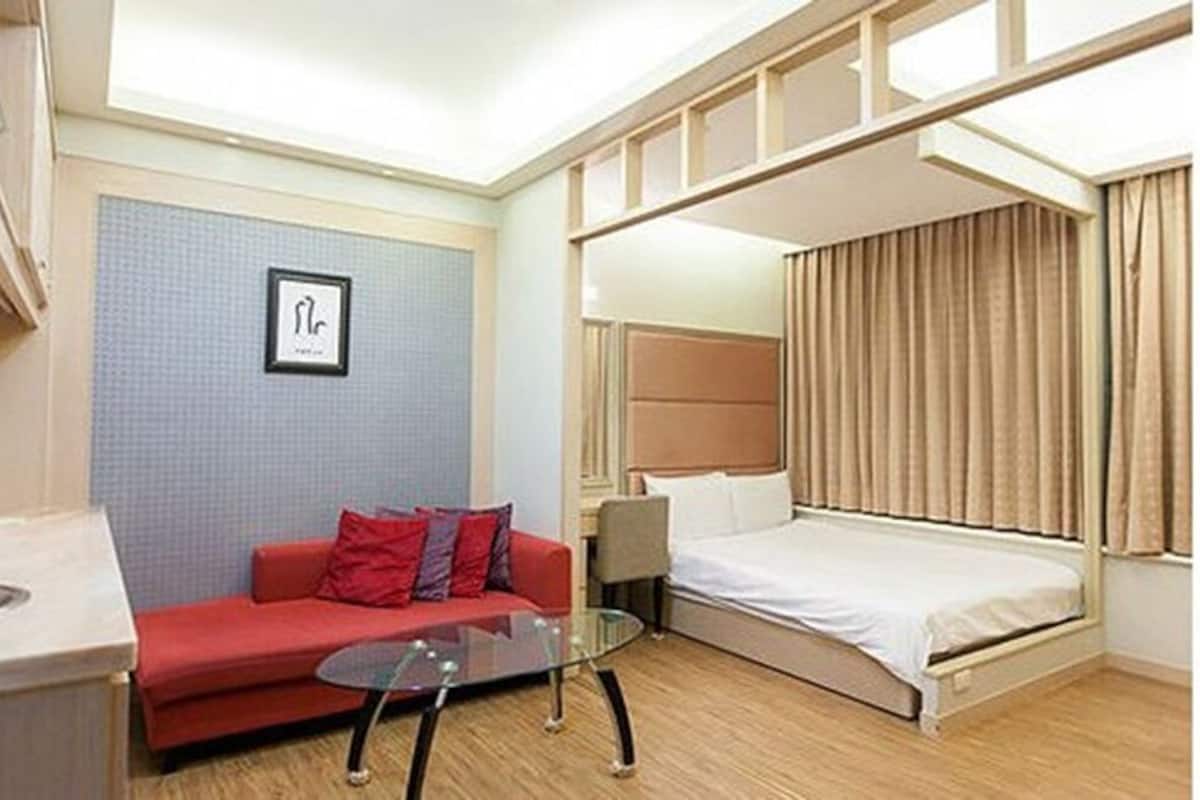Habitación de hotel con una cama litera, un sofá rojo, una mesita de centro de cristal y un cuadro en la pared.