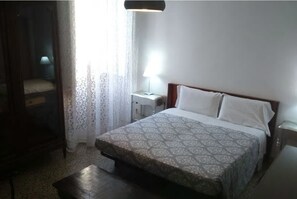 Ein Schlafzimmer mit Bett, Nachttisch, Lampe und Kleiderschrank.
