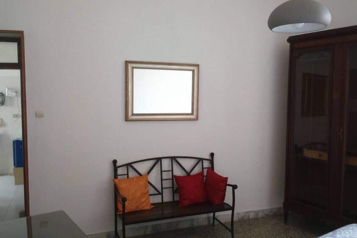 A room with a bench against the wall, a framed picture above it, and a cabinet to the right.