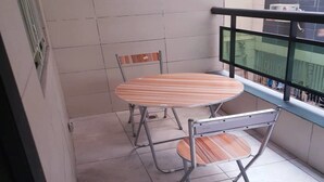 Ein kleiner Balkon mit Tisch und zwei Stühlen.