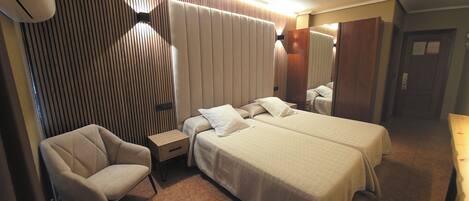 Una habitación de hotel con una cama grande, dos mesitas de noche, una silla y un espejo.
