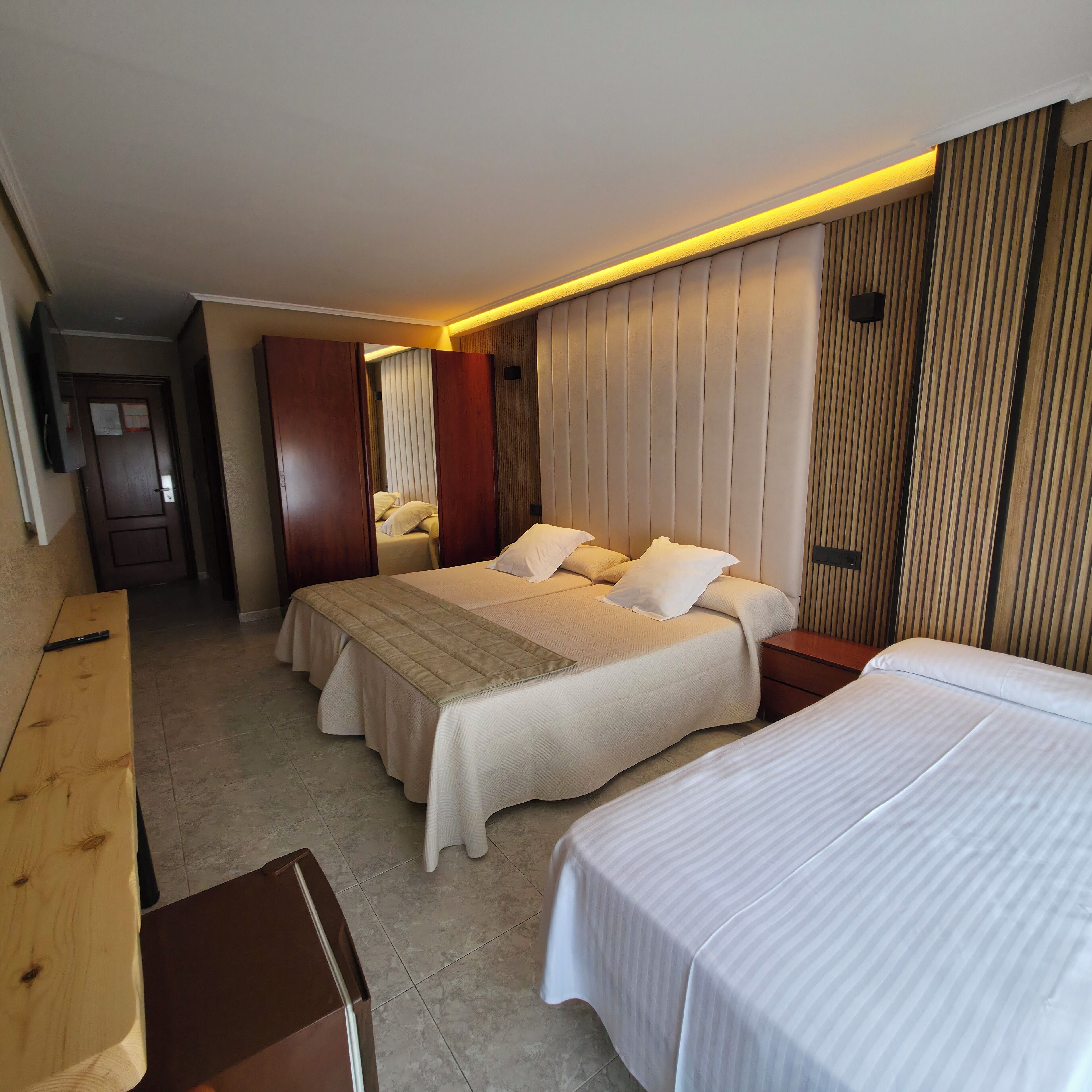 A hotel room with two beds, a wooden bench, and a small table.