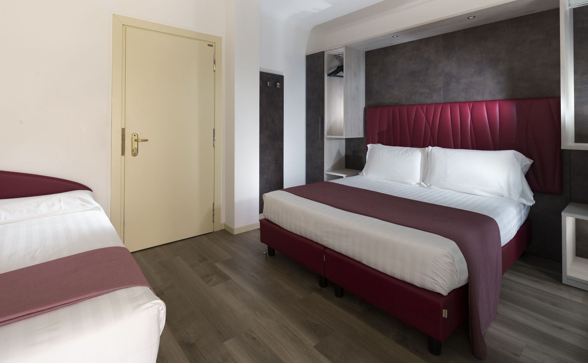 Una habitación de hotel con una cama grande, un armario y una puerta.