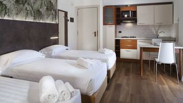 Ein Hotelzimmer mit zwei Betten, einem Schreibtisch und einer Küchenzeile.