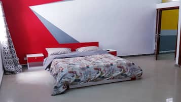 Une chambre à coucher avec un lit, une table de chevet, un mur rouge et une porte.