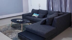 Uma sala de estar moderna com um sofá cinza escuro, uma mesinha de centro e um tapete estampado.