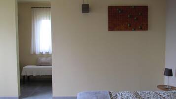 Een slaapkamer met een bed, nachtkastje, lamp, wandlamp en schilderij.