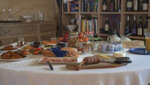 A table set with various food items, a selection of wine bottles, and a tea set. - Casa Vacanze San Stefanetto (Treiso)