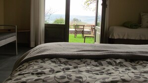 A bedroom with a bed, a chair, and a table outside a sliding glass door. - Casa Vacanze San Stefanetto (Treiso)