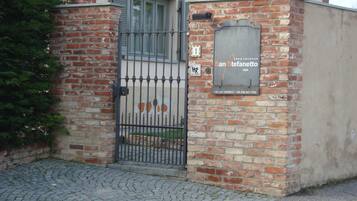 A brick building with a metal gate, a sign indicating 'casa vacanze San Stefanutto', and a small outdoor area with a paved surface.