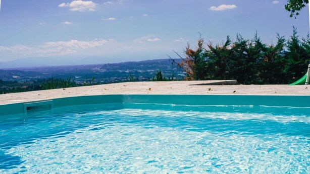 A clear blue swimming pool with a view of distant hills and a beach. - Casa Vacanze San Stefanetto (Treiso)
