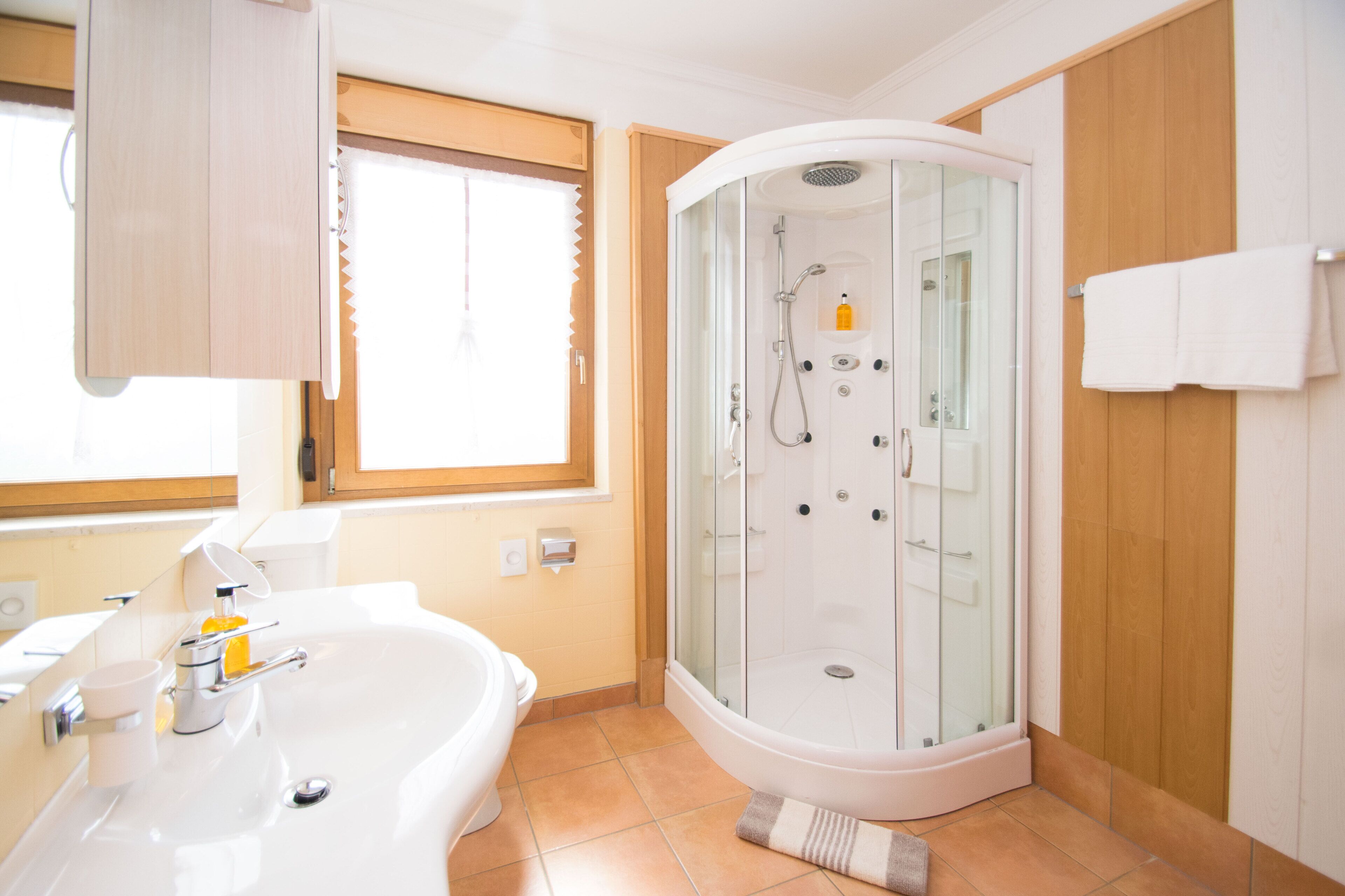 Une salle de bain moderne dotée d’une douche à parois de verre, d’une baignoire et d’une fenêtre laissant entrer la lumière naturelle.