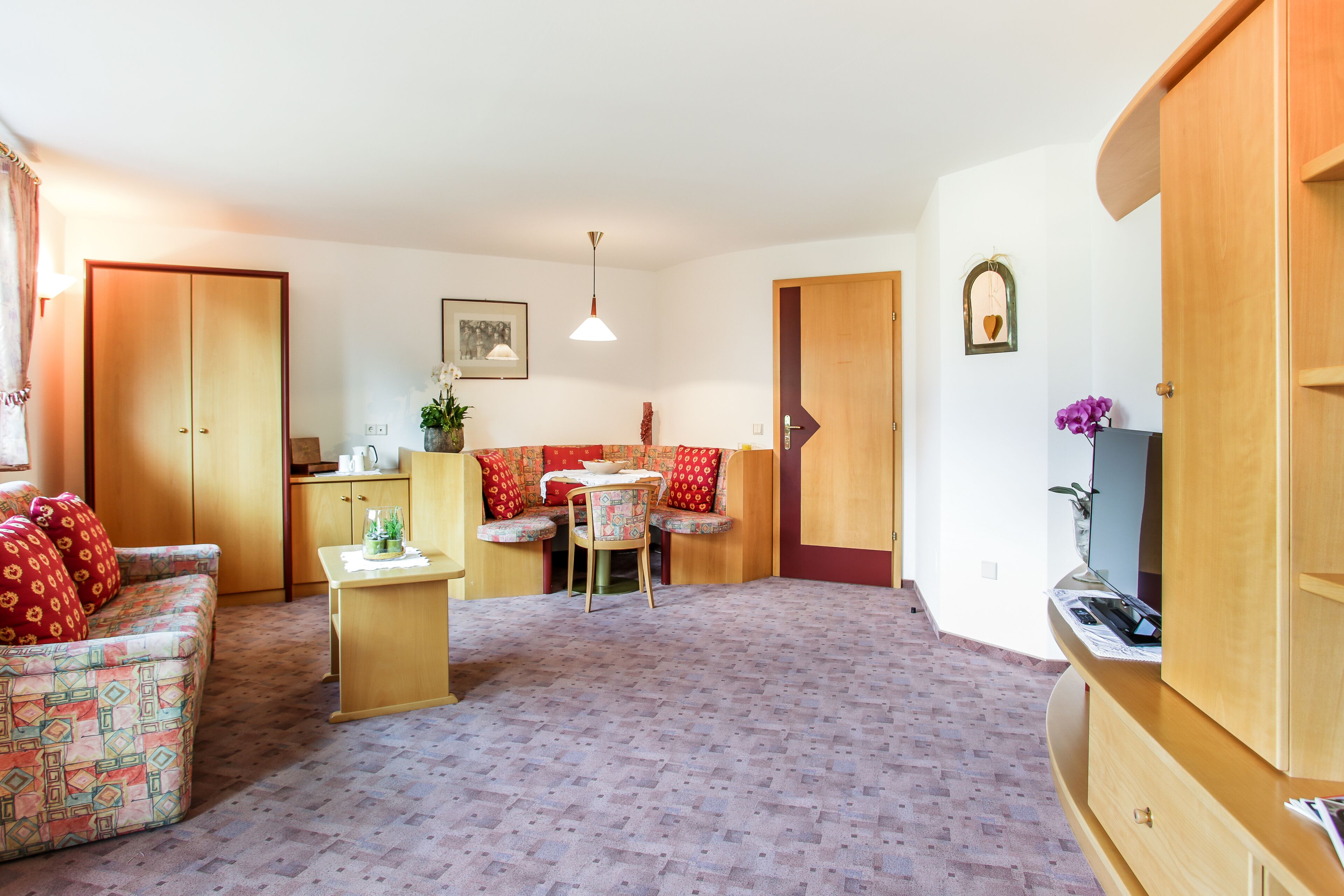 Un salon comprenant un canapé, une petite table, un fauteuil, un meuble en bois et une porte.