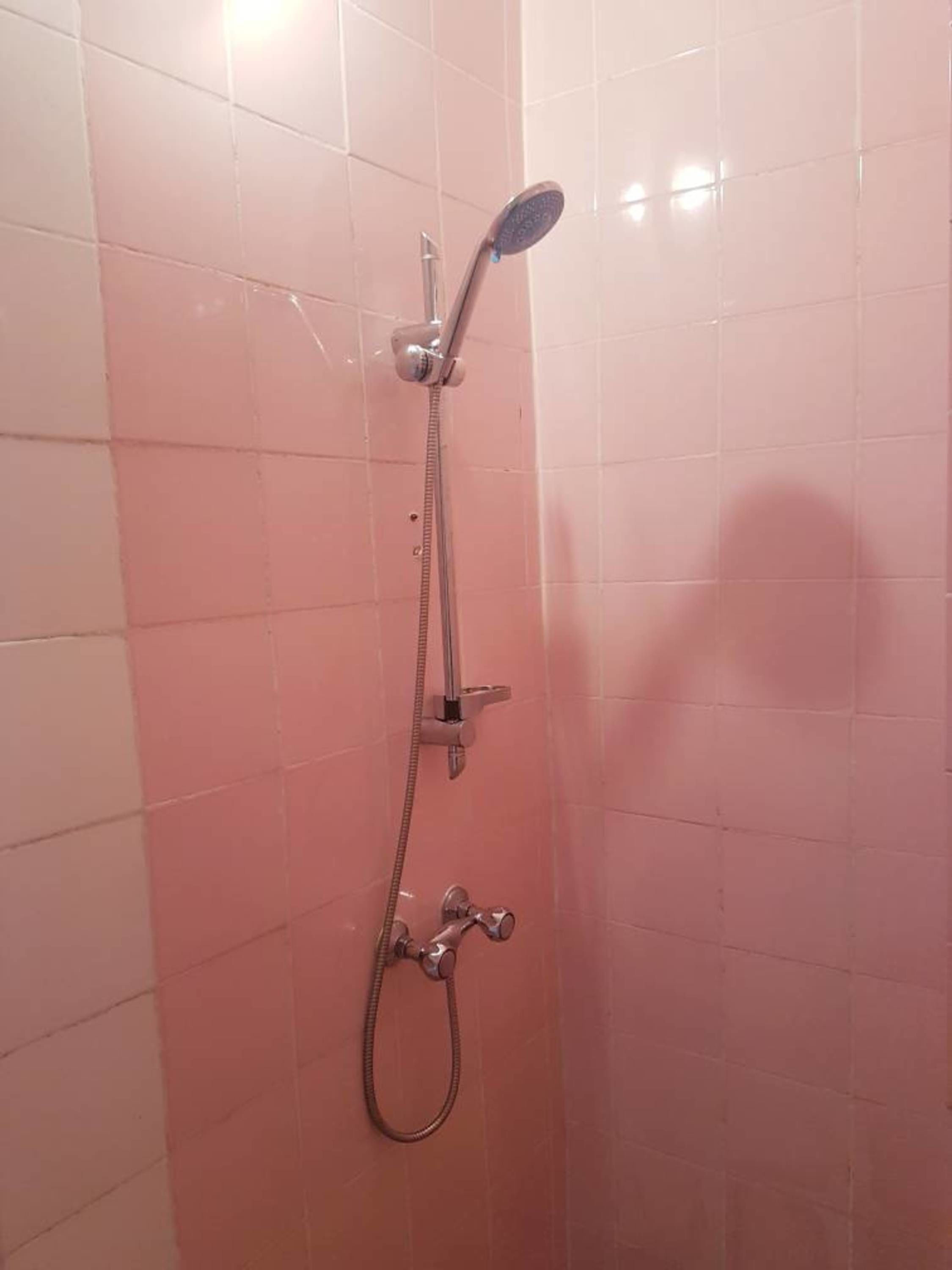 A shower with a handheld showerhead and a wall-mounted faucet.